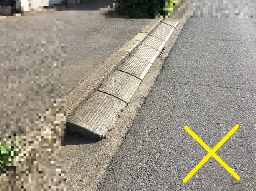 乗り入れブロックが設置された道路脇に黄色でバツ印が書かれた写真