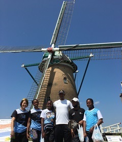 オランダ風車「リーフデ」の前で、ボツワナのソフトボール選手たちが笑顔で並んでいる記念写真