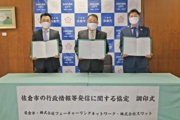 両手で協定書を持って立っている3名の男性の写真
