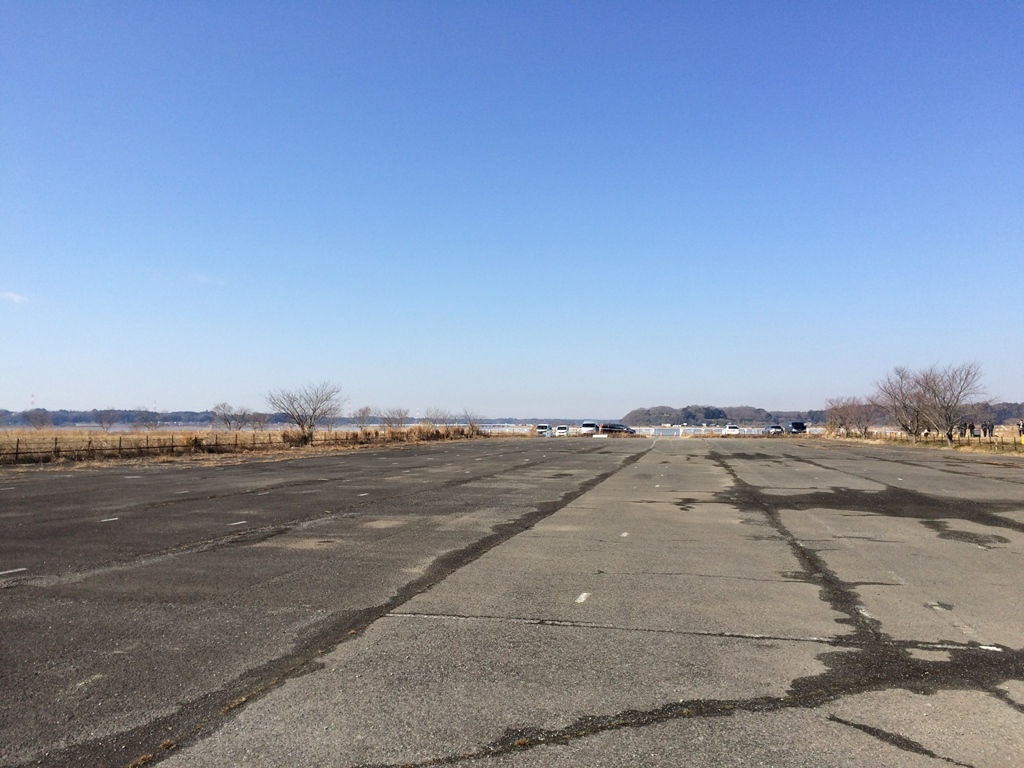 奥の方に駐車している車が写る広い駐車場の写真