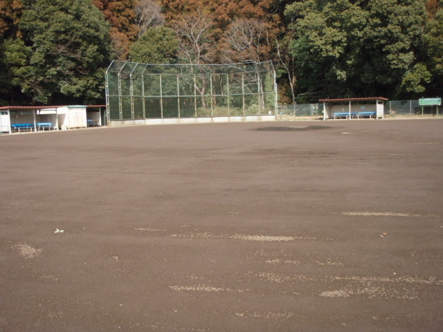 土のグラウンドで、バックネットがあり、左右にペンチ席が設けられている野球場の写真