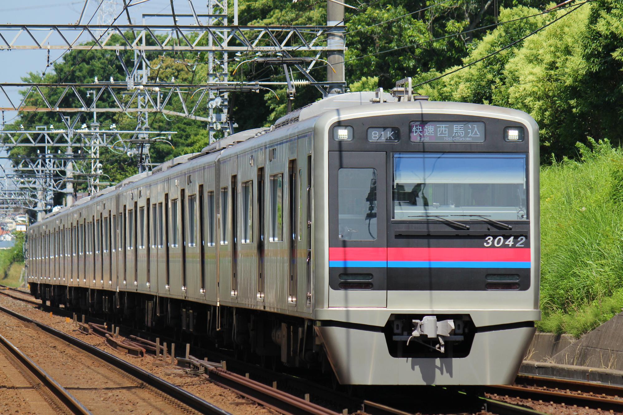 前面に赤と青の線が入った電車が線路を走っている写真