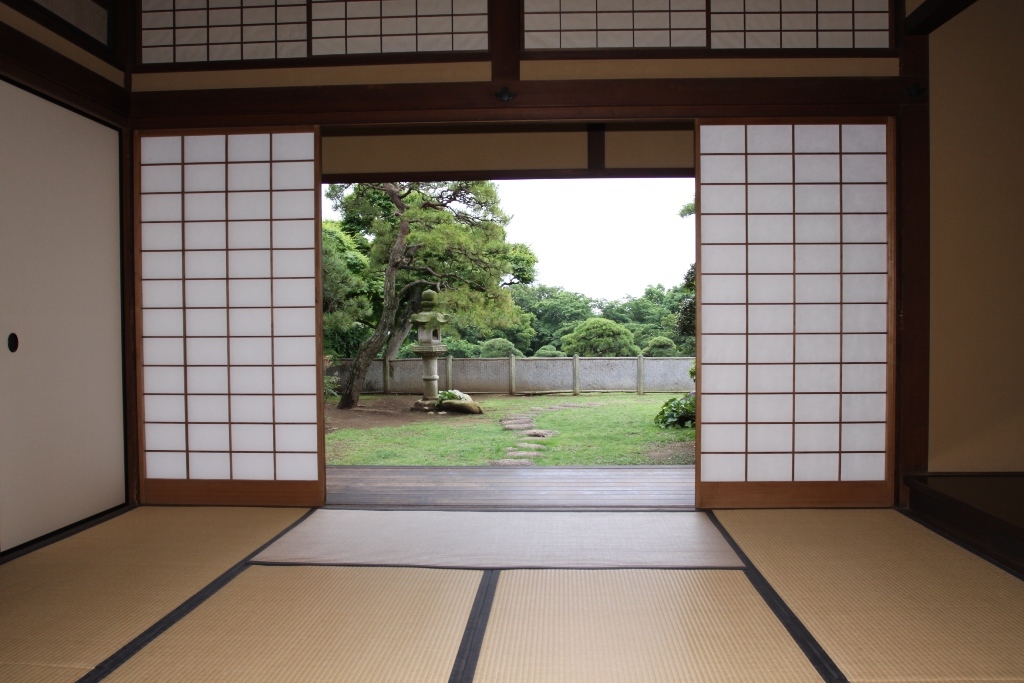 畳の敷かれた和室と和室から見えるきれいに整備されてた庭園の写真