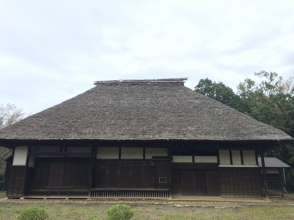 藁葺き屋根の屋根で、白い壁に木目の壁や窓がある旧増田家住宅の外観写真