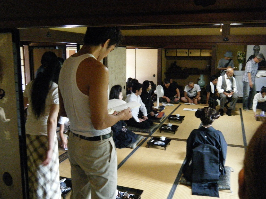 和室で撮影が行われており、俳優の方々が並べられたお膳の前に座り、演技をしている様子の写真