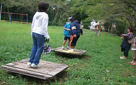 親子が木製のバランス床に乗って遊んでいる佐倉第二街区公園の写真