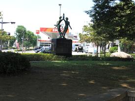 生垣の隣に人物の形をした大きな銅像が設置されている萌の広場の写真