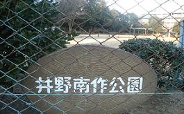 フェンスの内側に白文字で「井野南作公園」と書かれてある看板が設置してあるの写真