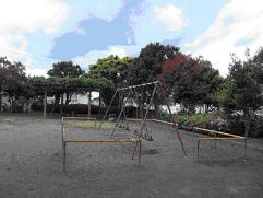 周囲を木々に囲まれた園内にブランコが設置されている若宮台公園の写真