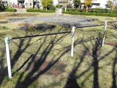 周囲の木々の影が鉄棒に写り込んでいる八幡台1号公園の写真