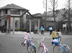 自転車を停めている奥の広場で遊んでいる子供たちの写真