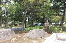 緑豊かな木々の手前に2つの大きな石が置いてある園内の写真