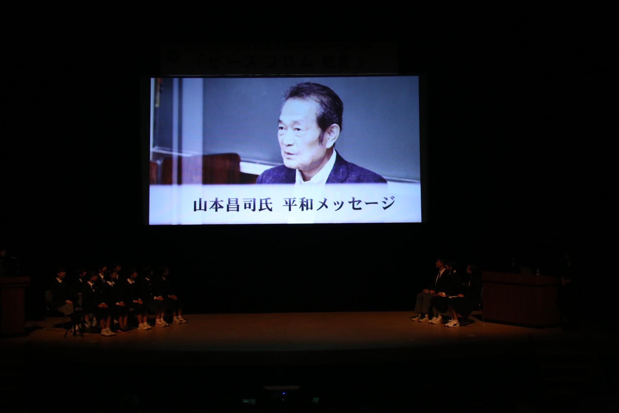 プロジェクトスクリーンに映る山本昌司さんの写真