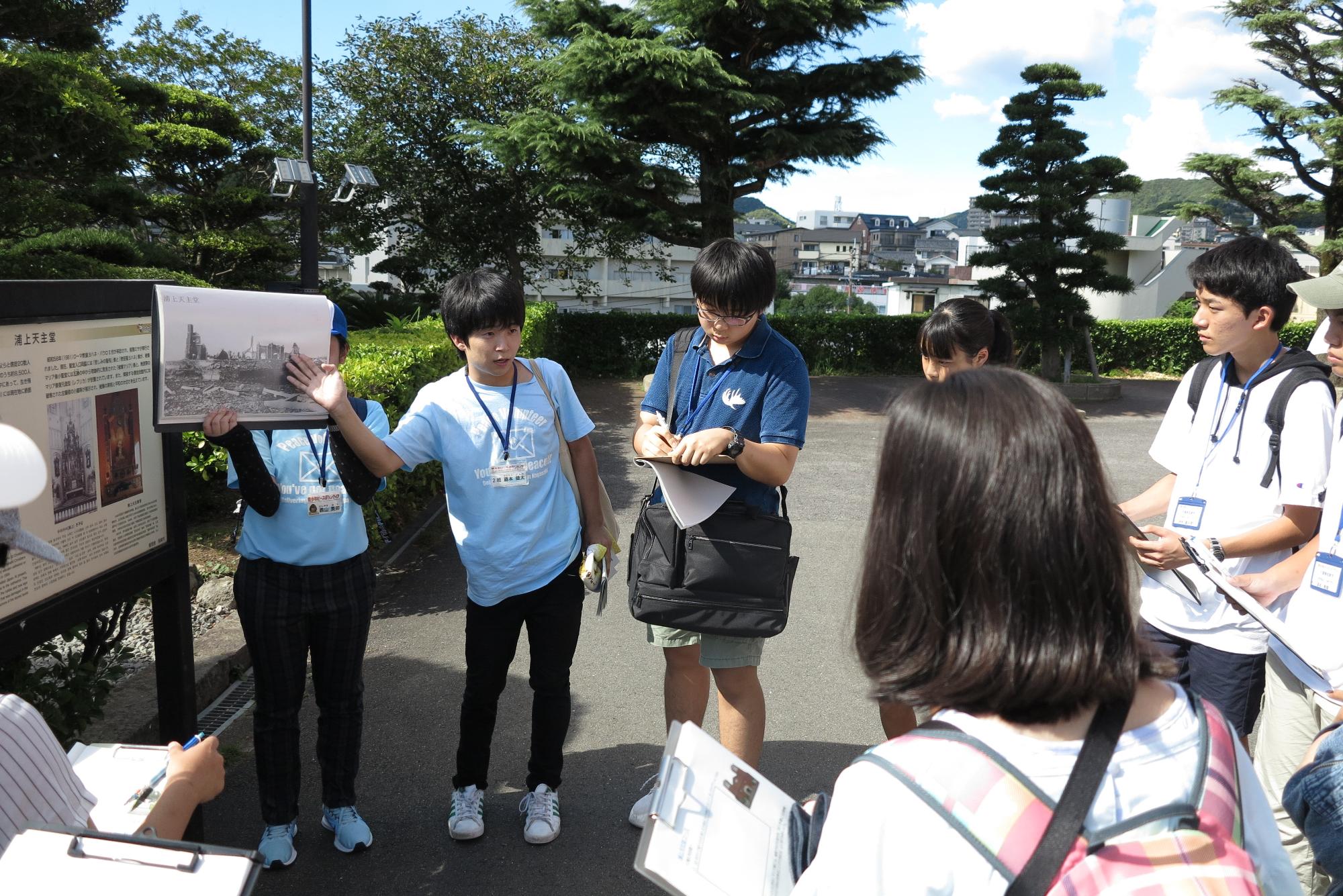 青少年ピースフォーラムの運営ボランティアの方が資料を見せながら生徒たちに説明をしている写真