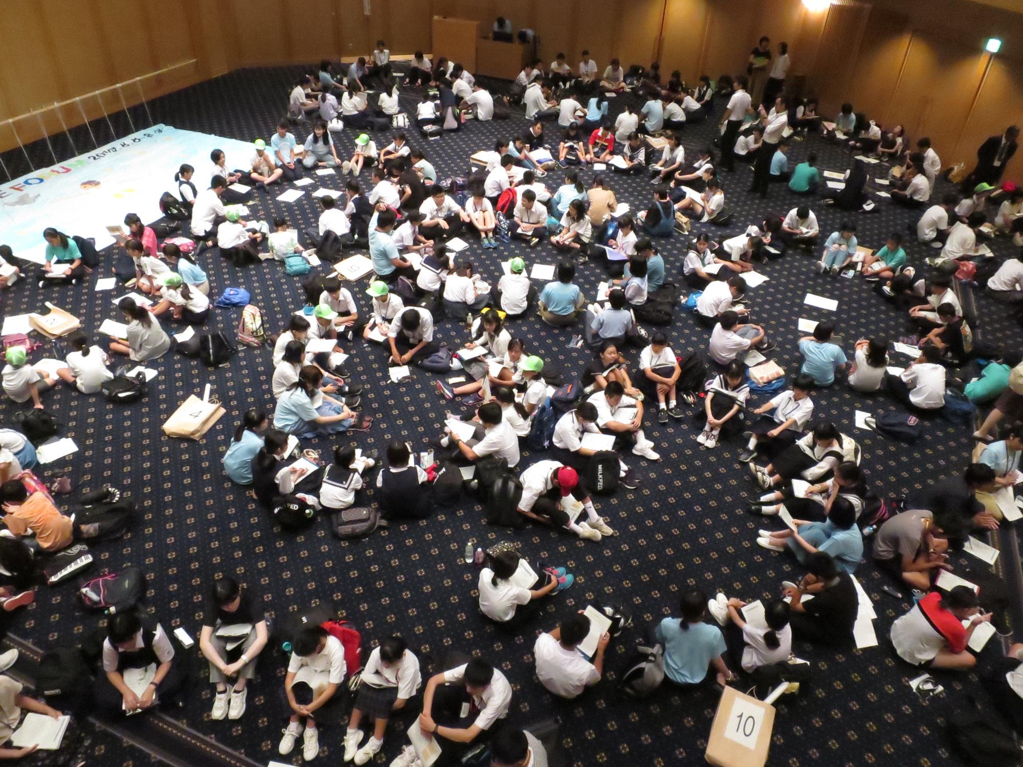 床の上に沢山の生徒たちが座って意見交換をしている様子を上から写している写真