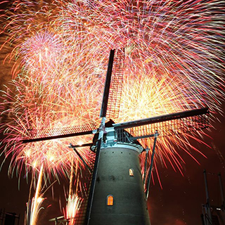 オランダ風車の奥に見える空一面の鮮やかな花火の写真
