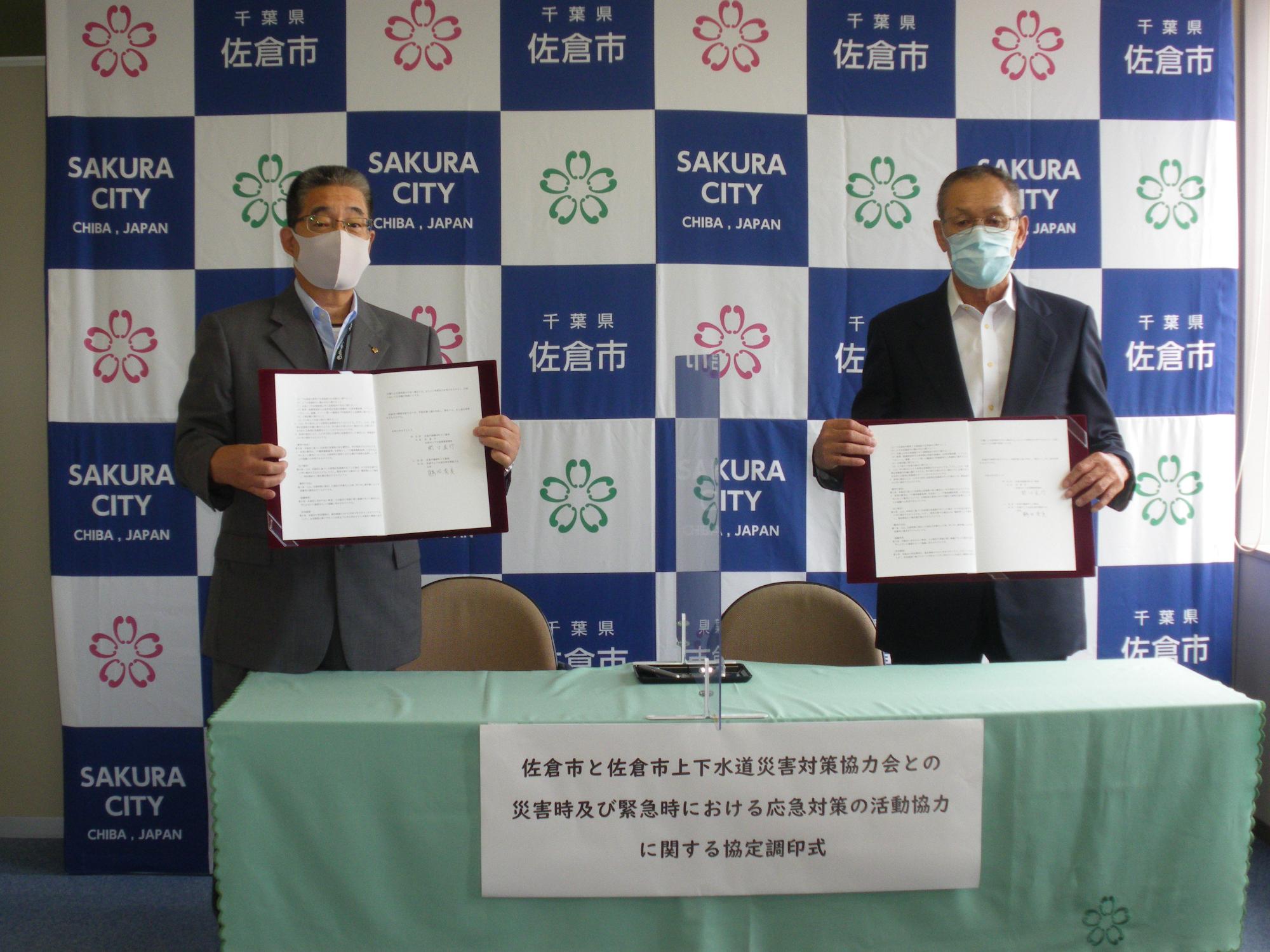 関口直行氏と鶴田秀美会長が協定書を持って並んで立っている写真