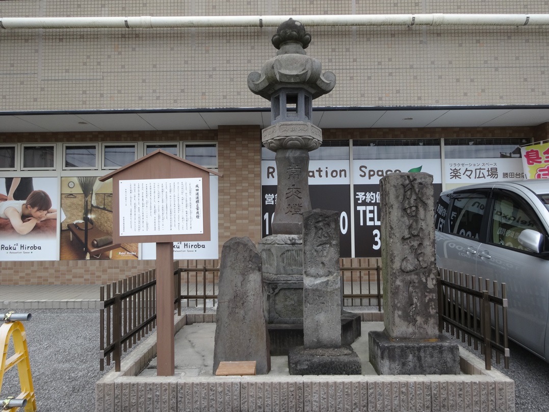 店舗駐車場横にブロックで囲われている、佐倉道（成田街道）の道標を正面から写した写真
