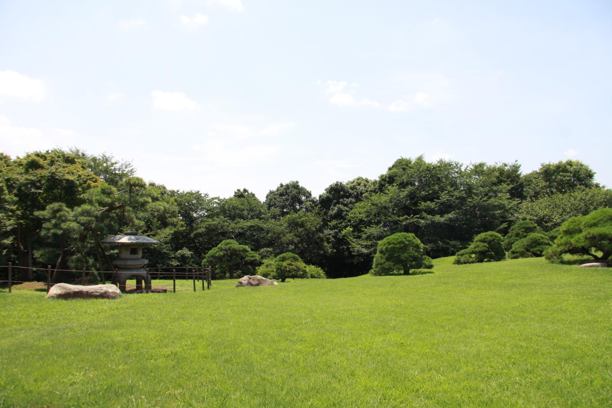 青空の下緑豊かな旧堀田正倫庭園全体を写した写真
