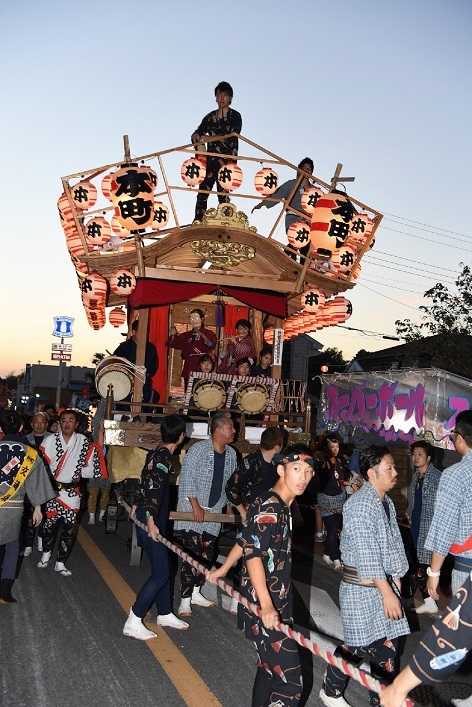 灯りがともされた「本町」の提灯がついた神輿がお祭りで引き廻されている写真