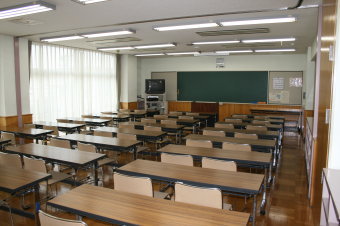 前方にはテレビと黒板、講演台が設置され、2人掛けの長机が3列に前方から並べられている学習室1の写真