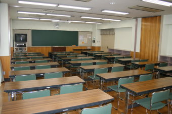 前方には黒板、テレビ、講演台が設置され、2人掛けの長机が3列に前方から並んでいる学習室2の写真