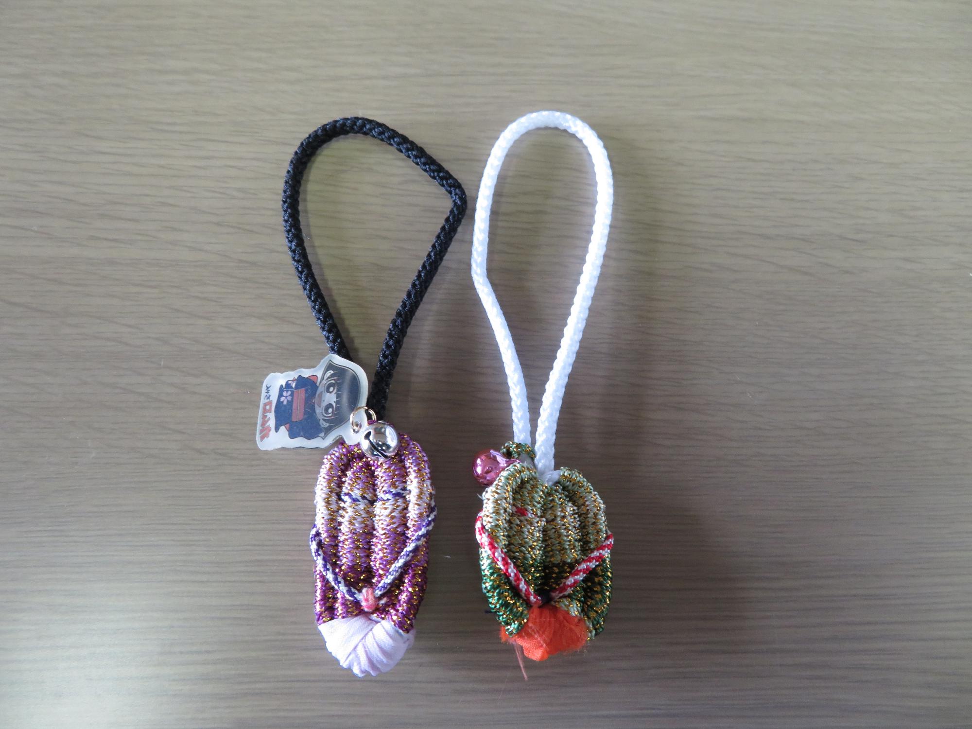 ピンクや紫と緑や赤で編み込まれ、ストラップにするための紐がついたミニ草履の写真
