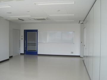出入り口の扉の横にホワイトボードが設置されている会議室の写真