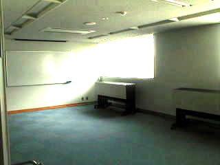 ホワイトボードや折り畳まれた机がある部屋に光が差し込んでいる学習室の写真