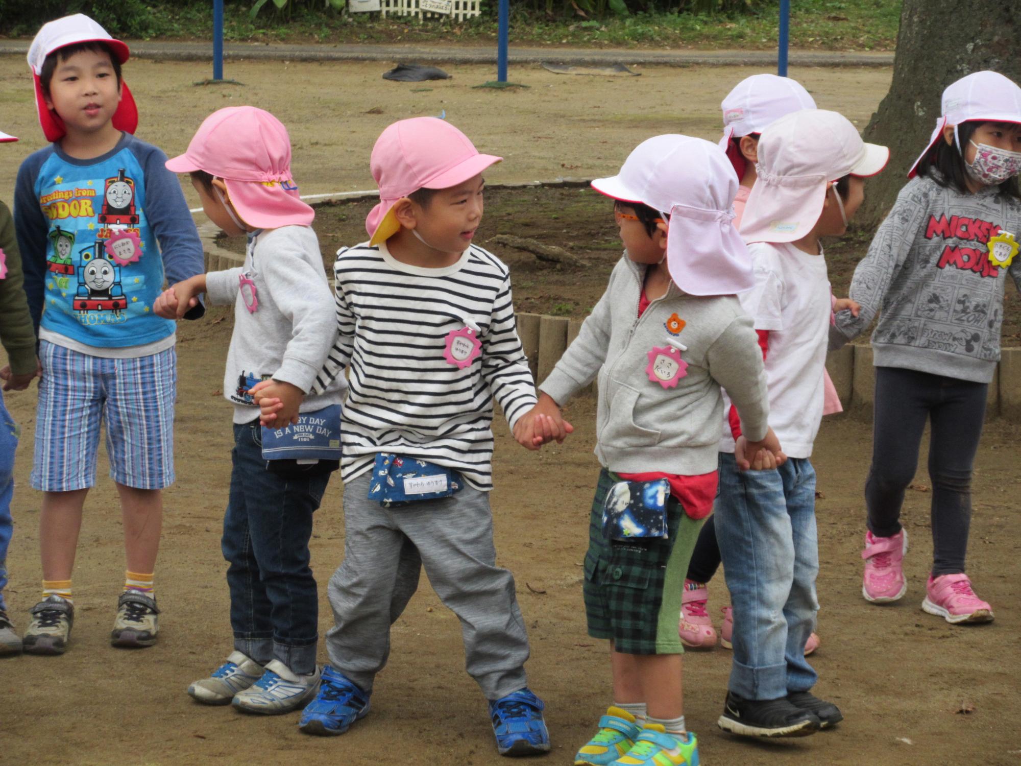ピンクの帽子を被った園児たちが手をつない立っている写真