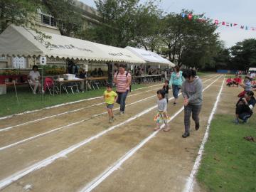白線が引かれたコースを3組の親子たちが一緒に走っている写真