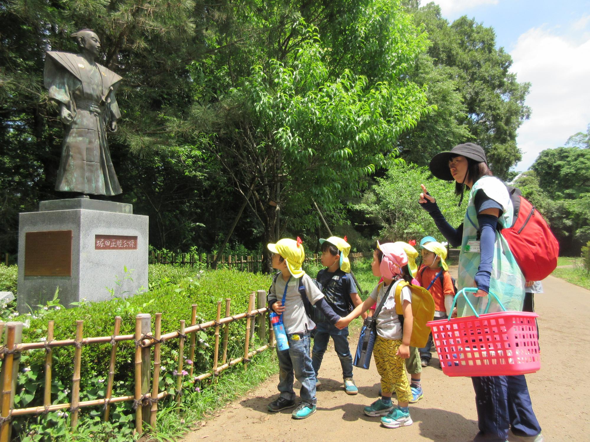 園児たちが手をつないで堀田像の前を歩いている写真