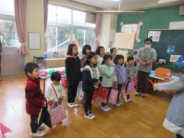 教室で園児たちと1年生たちがバッグを持って立っている写真