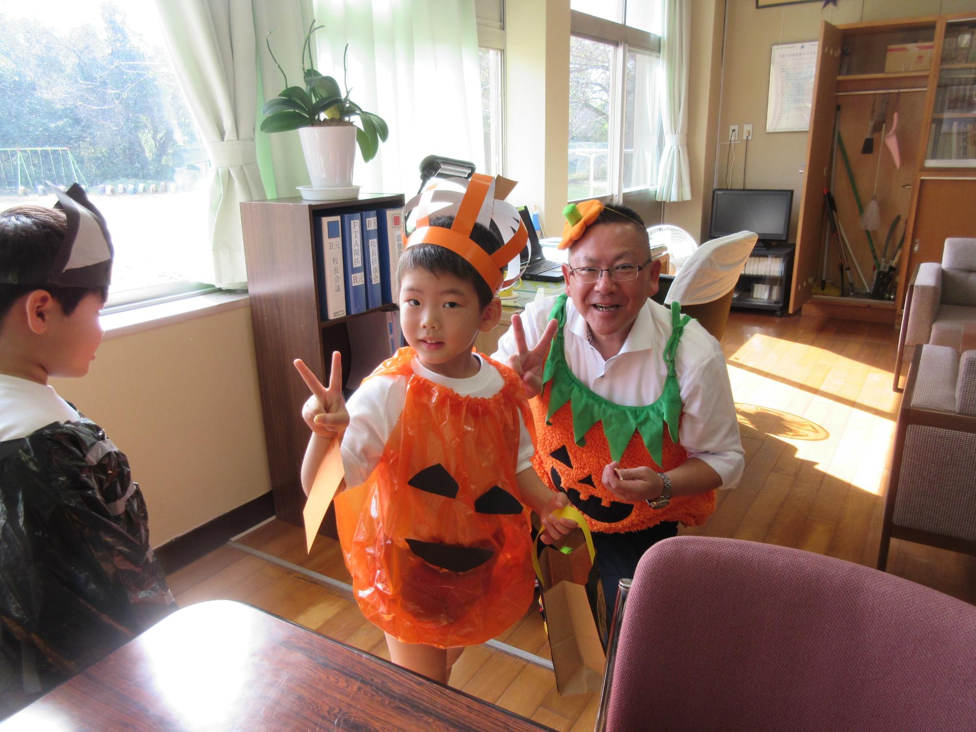 かぼちゃの恰好をした園児と園長先生が二人でピースをしている写真
