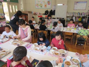 机の上にランチョンマット、お皿などが置かれ、園児たちが給食を食べている写真