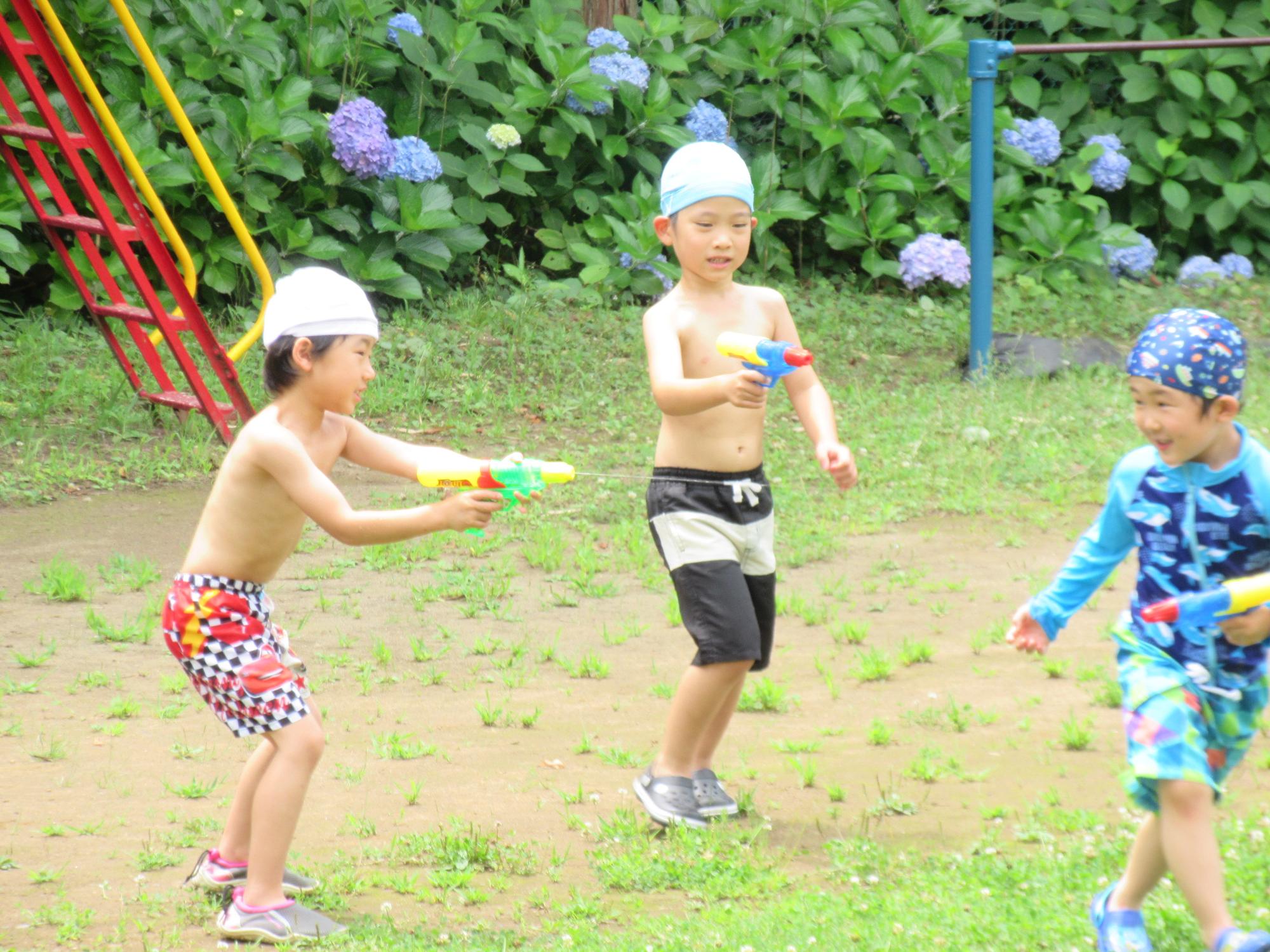 水着姿の園児たちが水鉄砲で遊んでいる写真