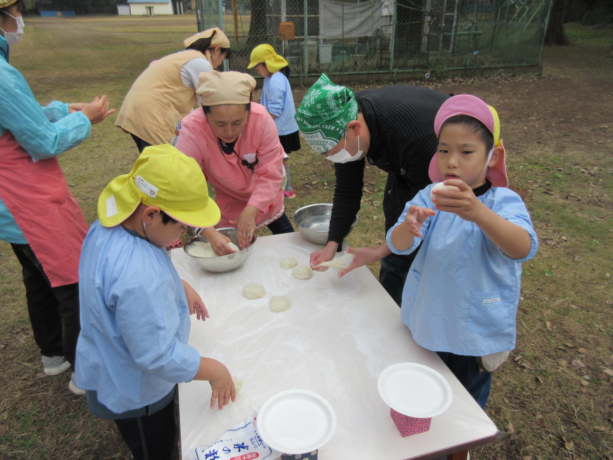 園児や、エプロンに三角巾を付けた職員が、餅を丸めている写真