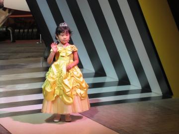 黄色のドレスを着た女の子が右手を振っている、ファッションショーの仕事に挑戦している写真
