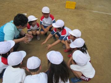白い帽子を被った園児や、小学生、職員が輪になって座り相談している写真