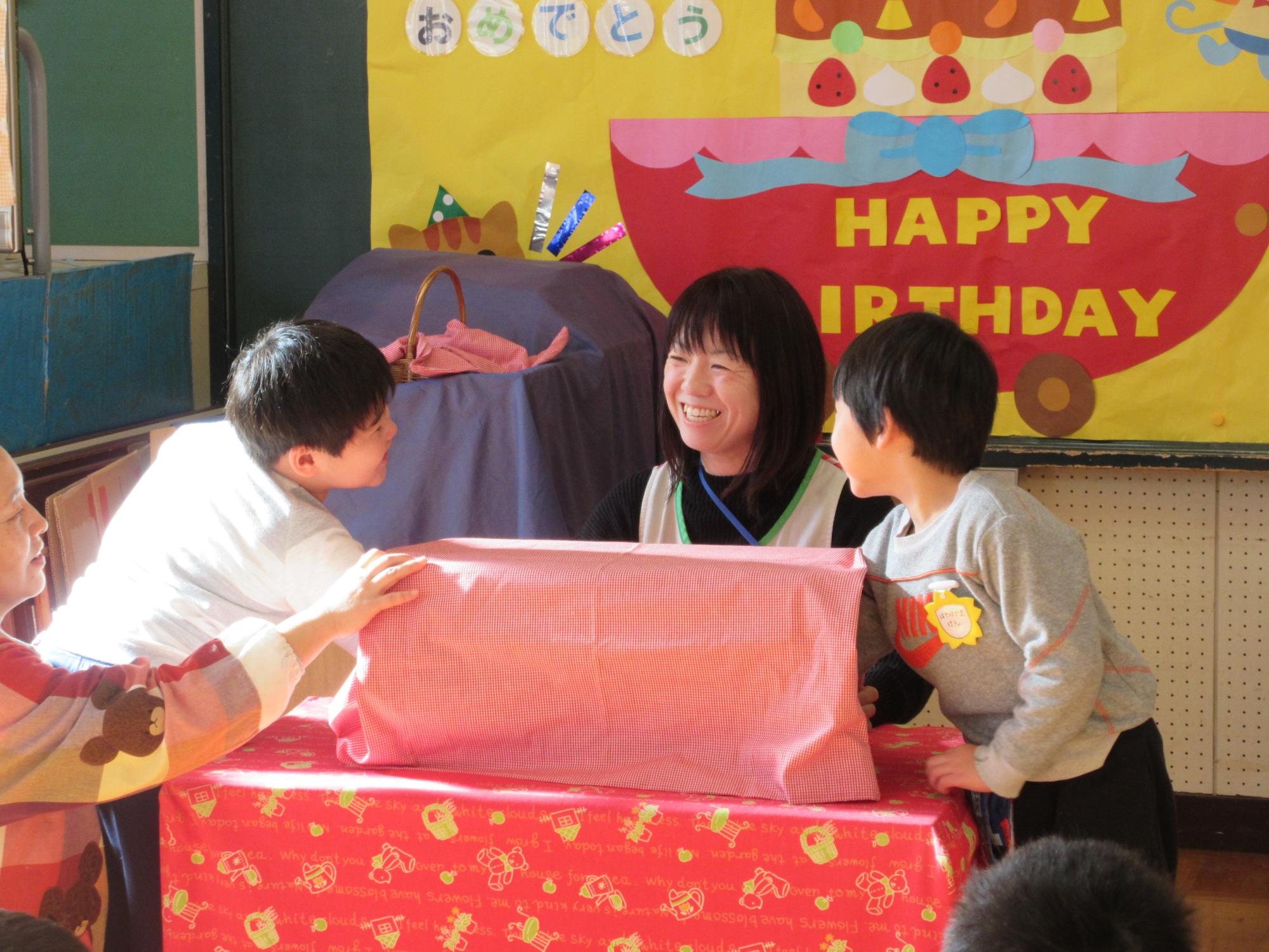 赤い布がかけられた箱の中に誕生月の二人の園児が手を入れている写真