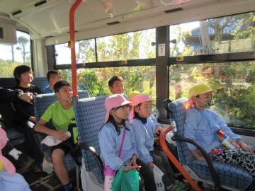 園児たちと小学生たちがバスの椅子に座っている写真