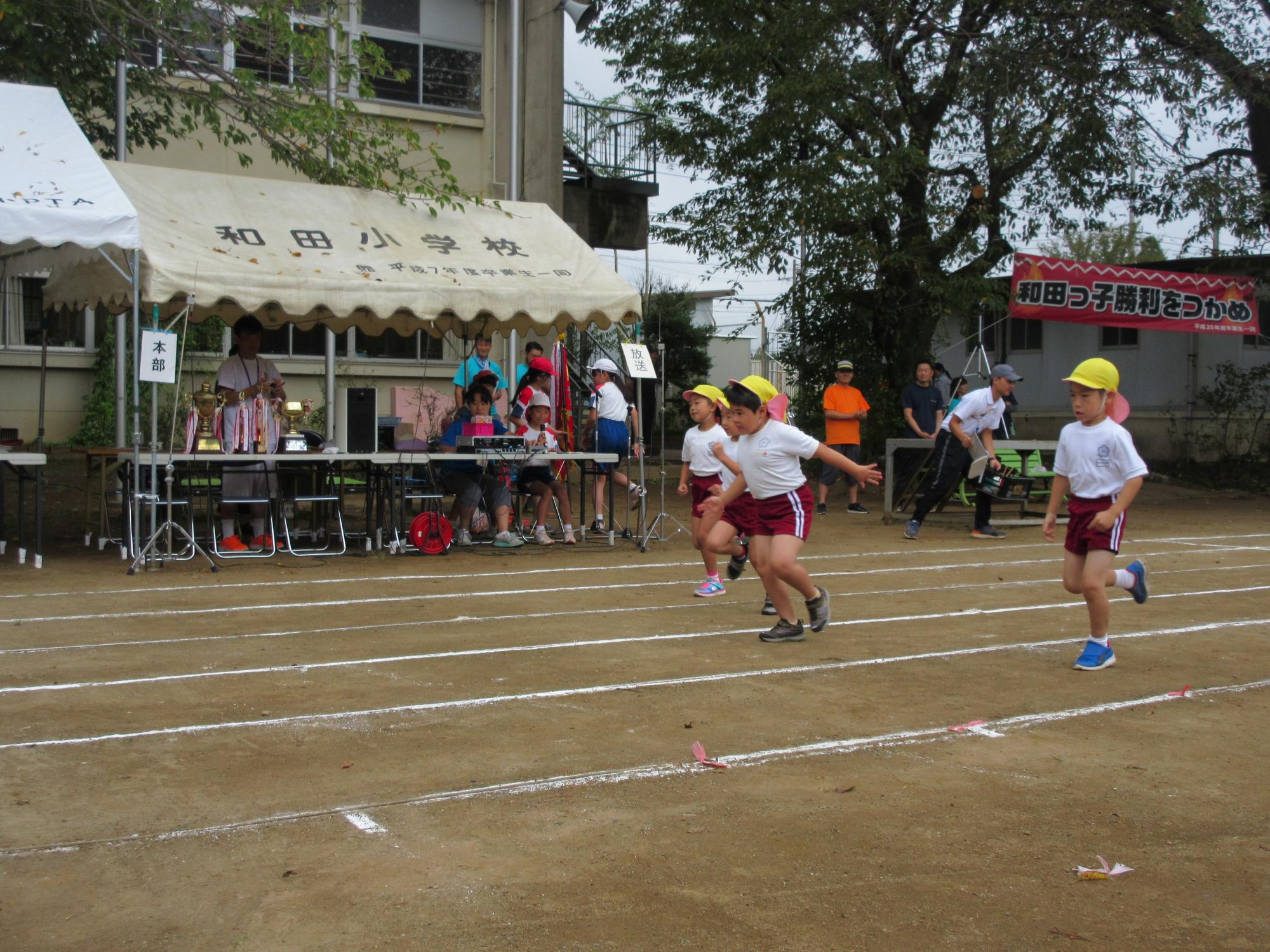 白線の敷かれたラインの中を園児3人が走っている写真