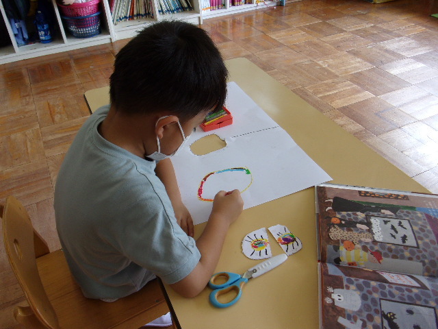 男の子の園児が、クレヨンを使って絵を描いている写真