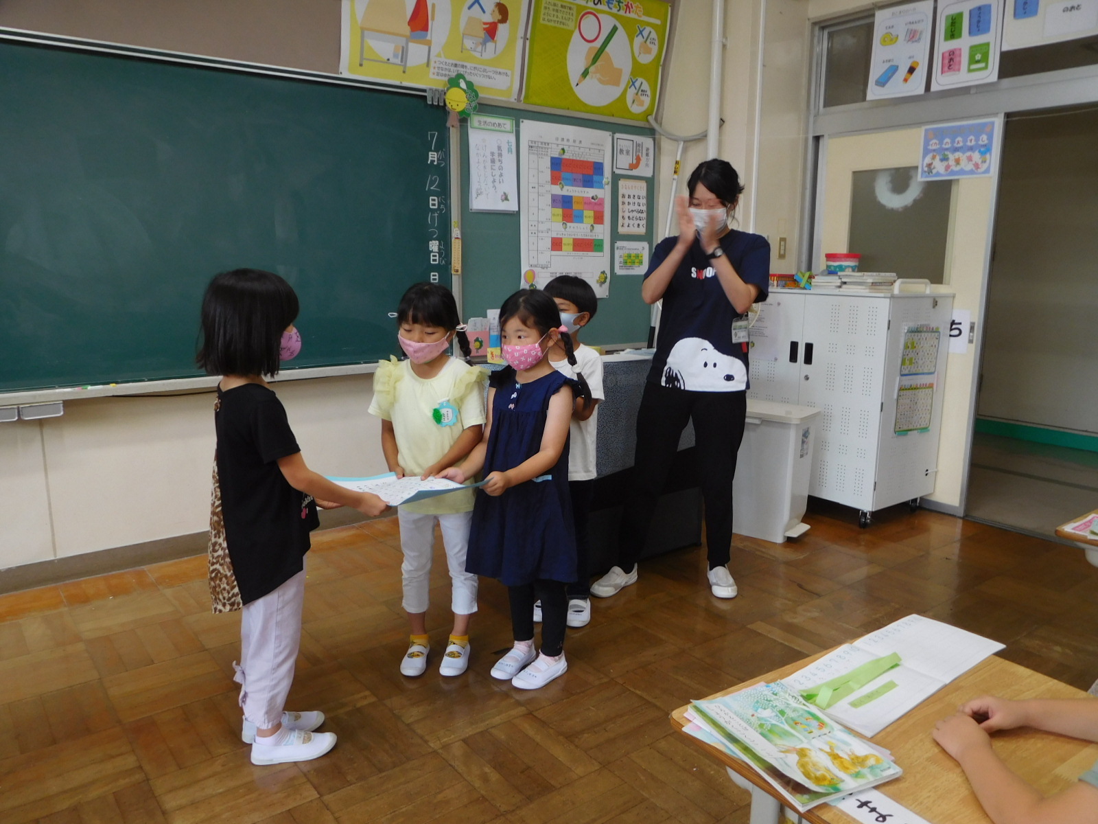 教室で、女児に招待状を手渡ししている園児の写真