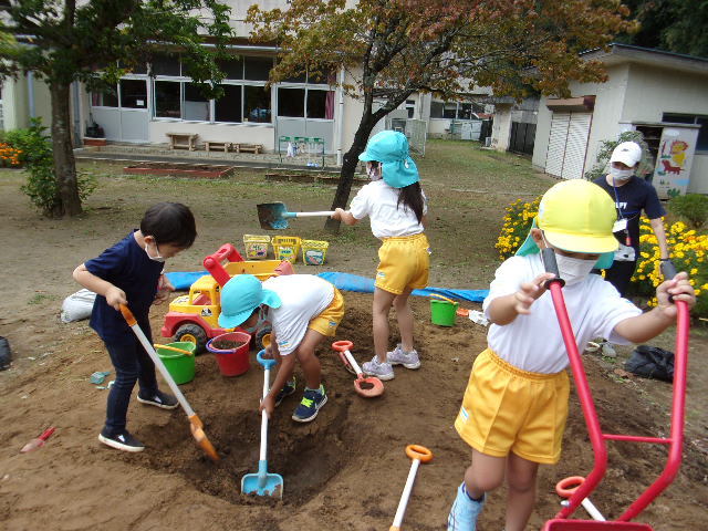 砂場でスコップを使って穴を掘っている子供たちの写真