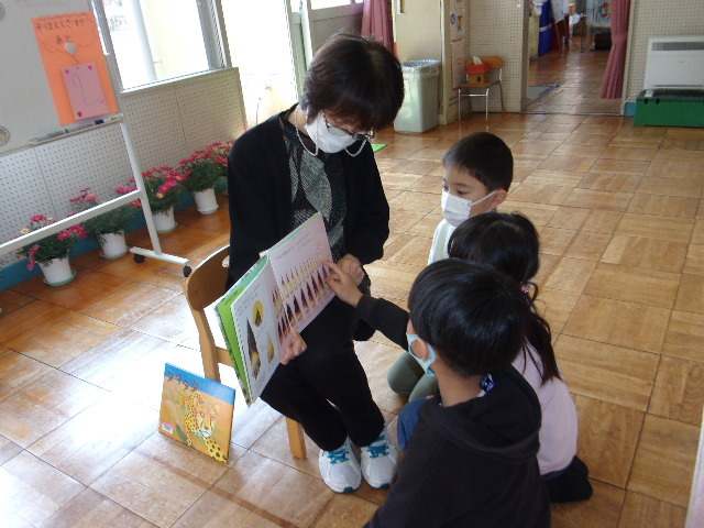 園児3名の前で、司書の先生が絵本の読み聞かせをしている写真