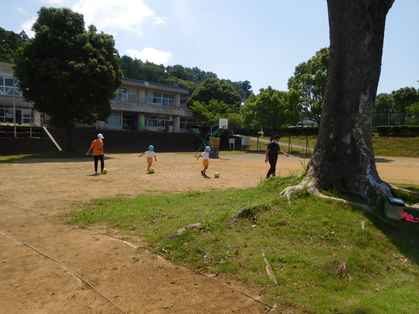 園長先生や女性、園児2名がサッカーをしている写真