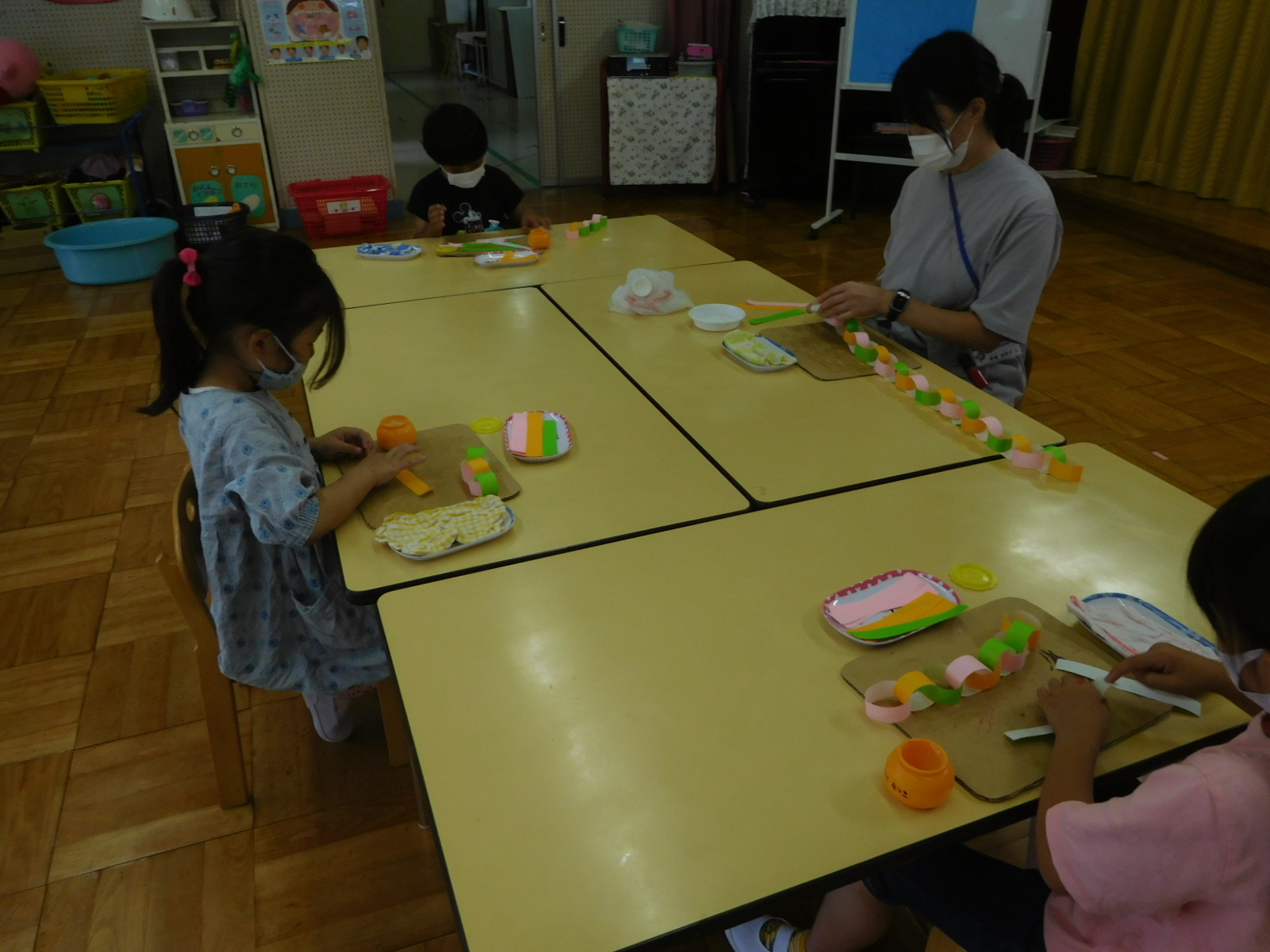 折り紙をつなぎ合わせて七夕の飾りつけを作っている園児の写真