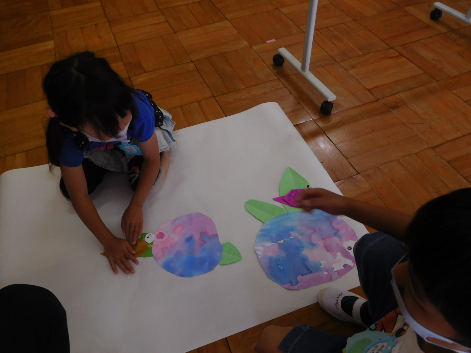 手作りのアジサイの横に、折り紙で作ったかたつむりを貼っている女の子の園児の写真