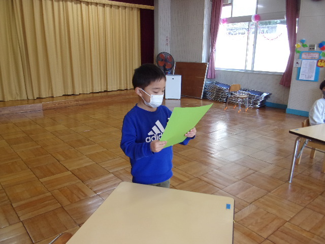 男の子の園児が、緑の紙を持って立っている写真